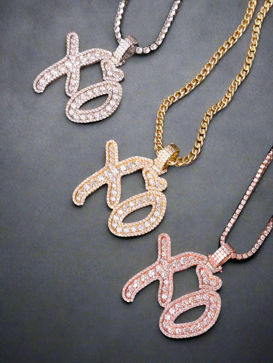 Three necklaces with 'xo' pendants on a dark woven surface